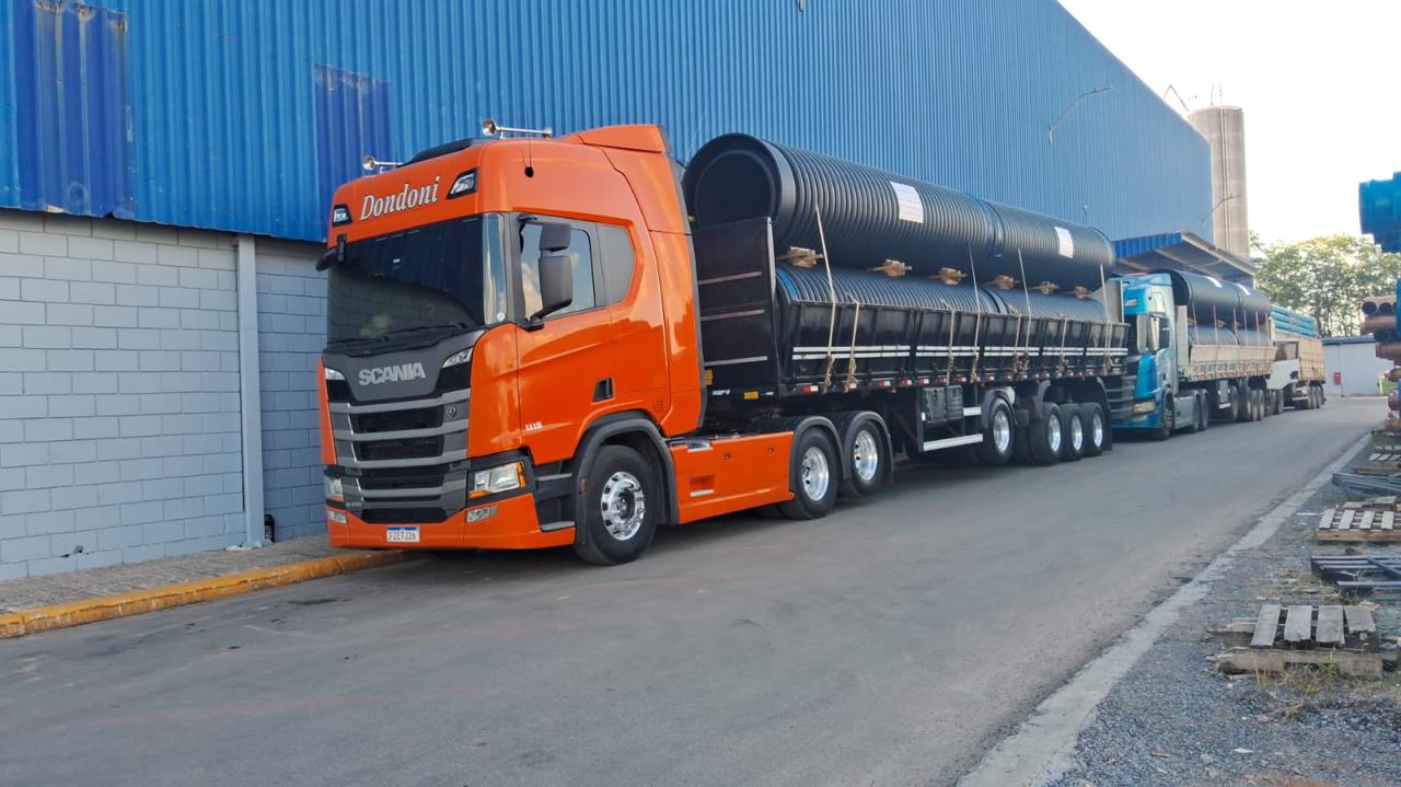 Caminhão Scania transportando tubos industriais em carroceria aberta
